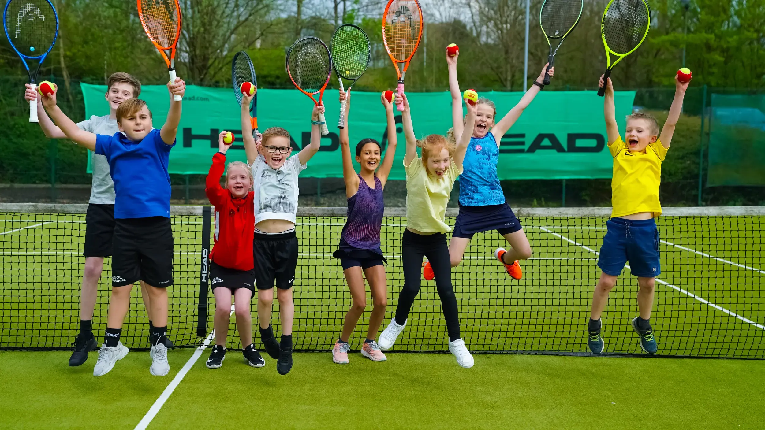 Children jumping holding tennis racquets