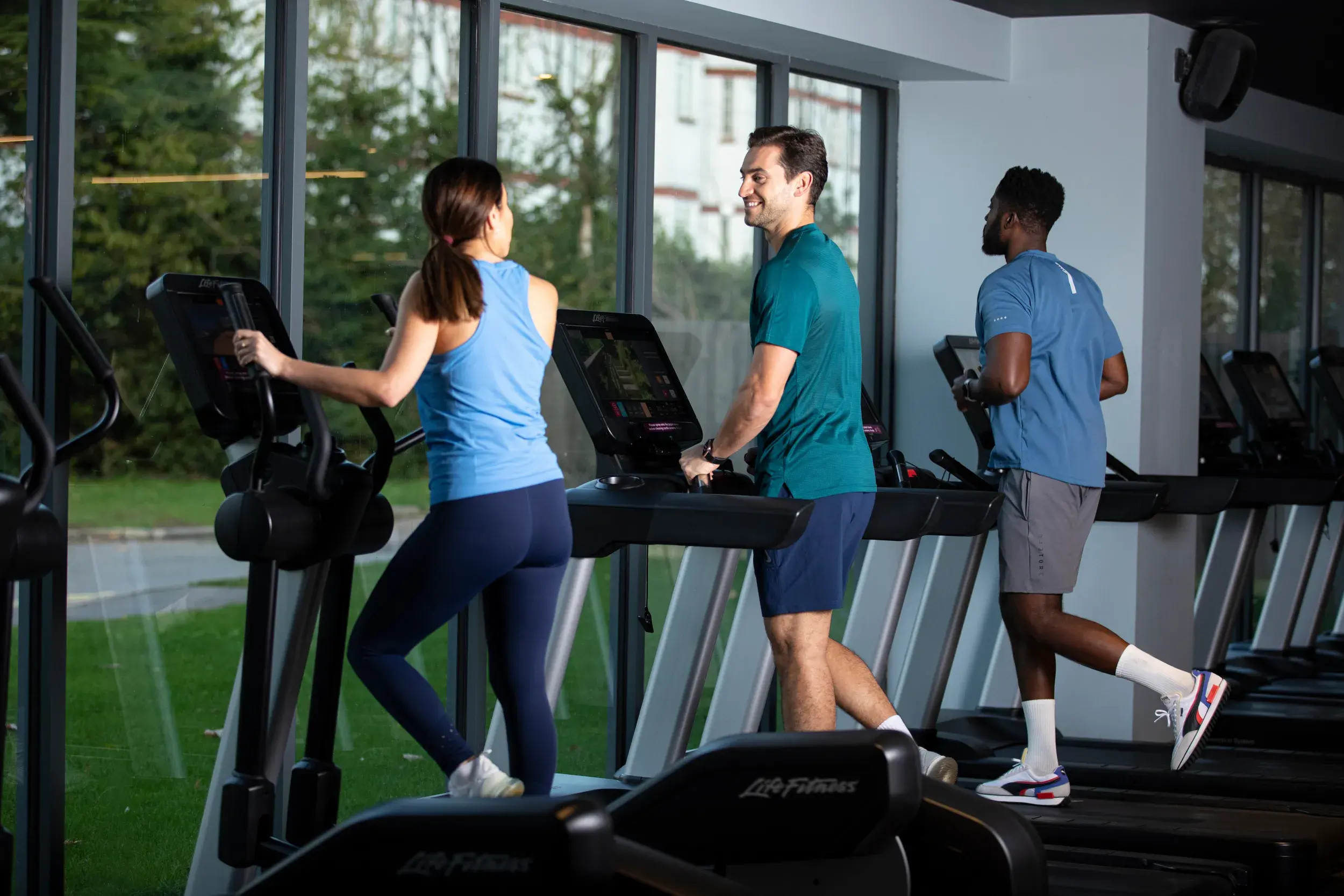 Three people running on a treadmill