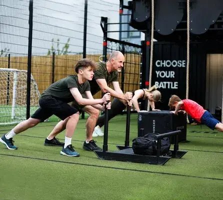 A father and son pushing a sled in a battlebox class