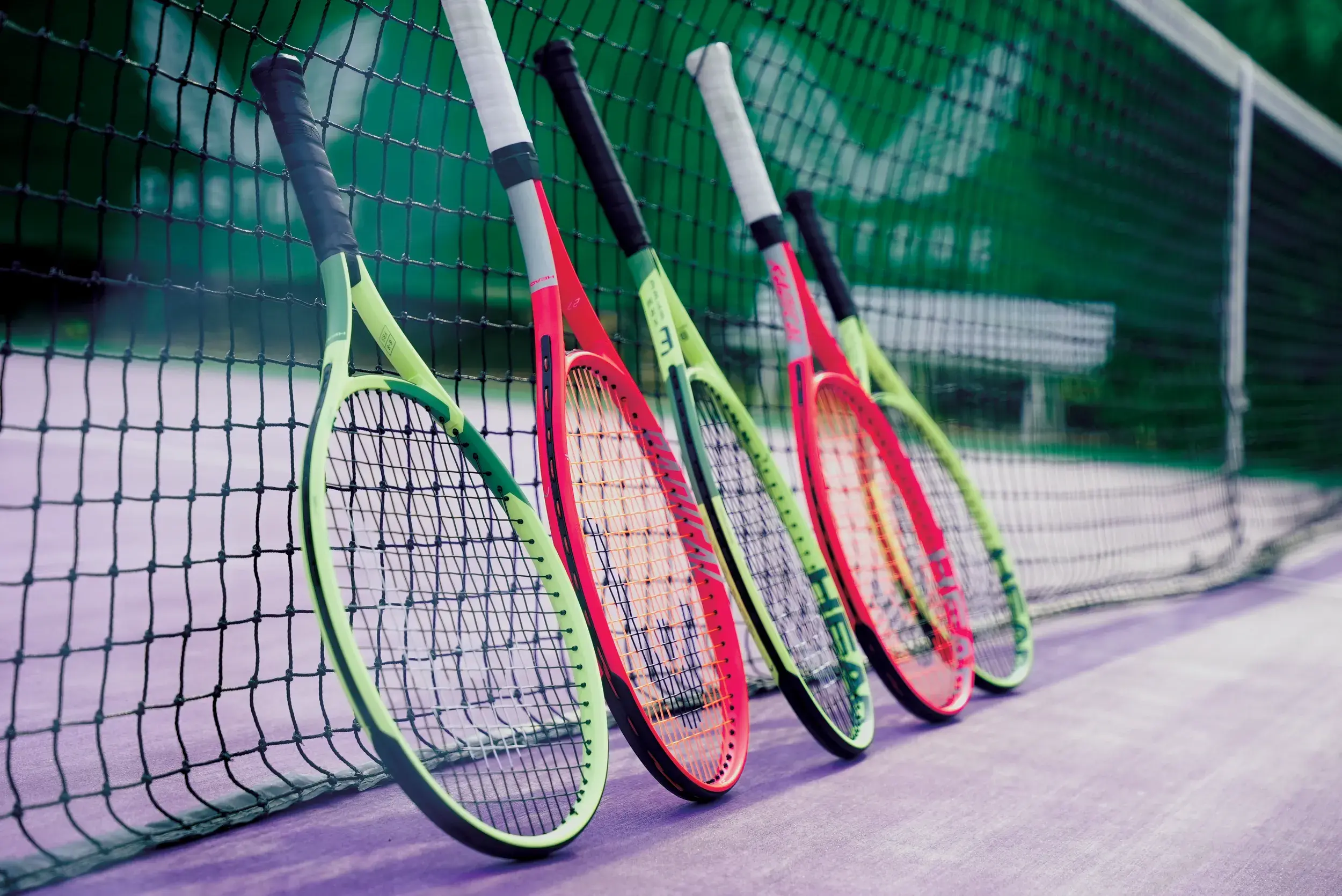 A row of tennis racquets up against a net