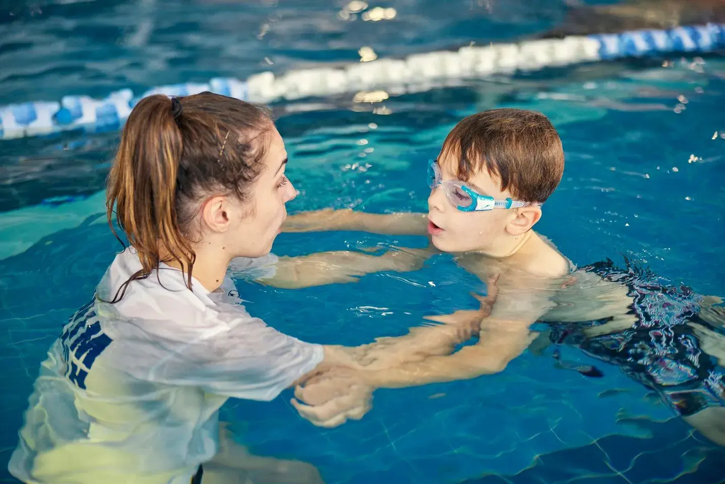 A young boy in the swimming pool with the an instructor