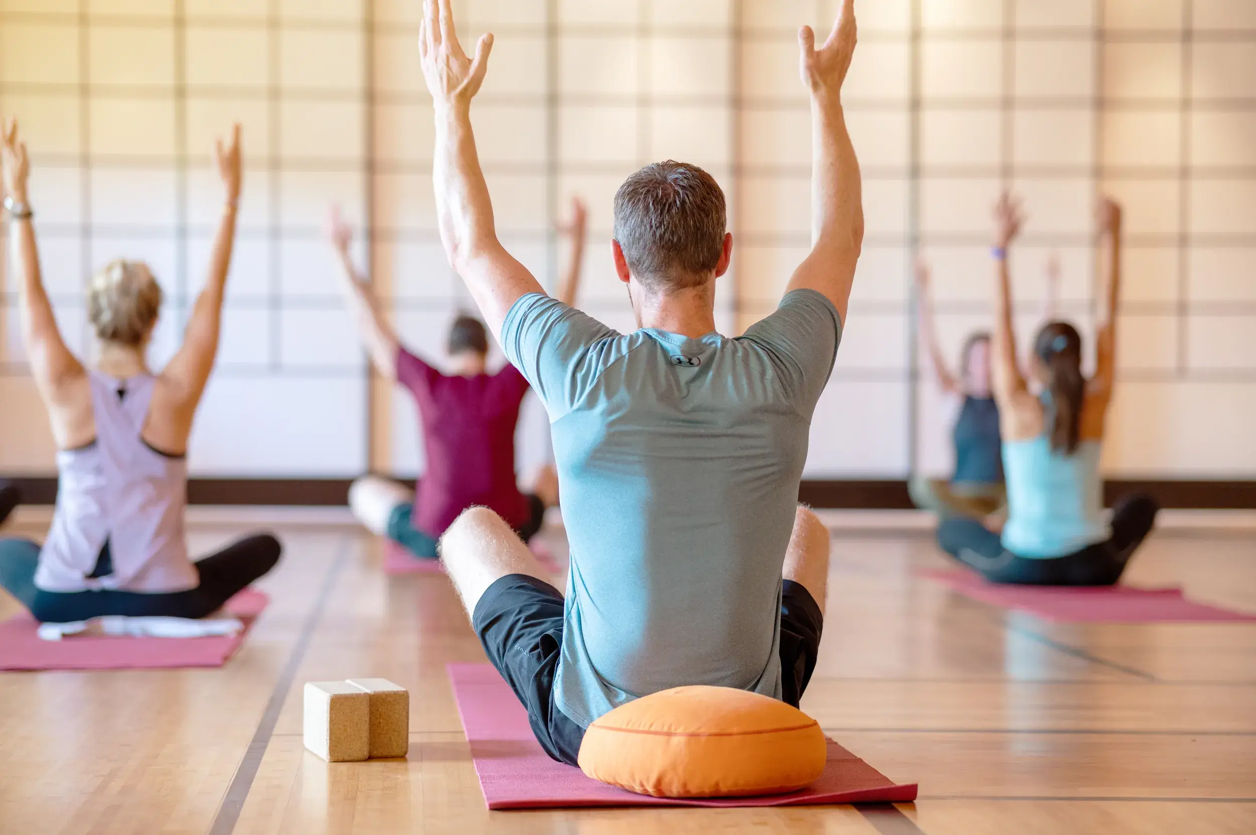 A man stretching upwards in a yoga class